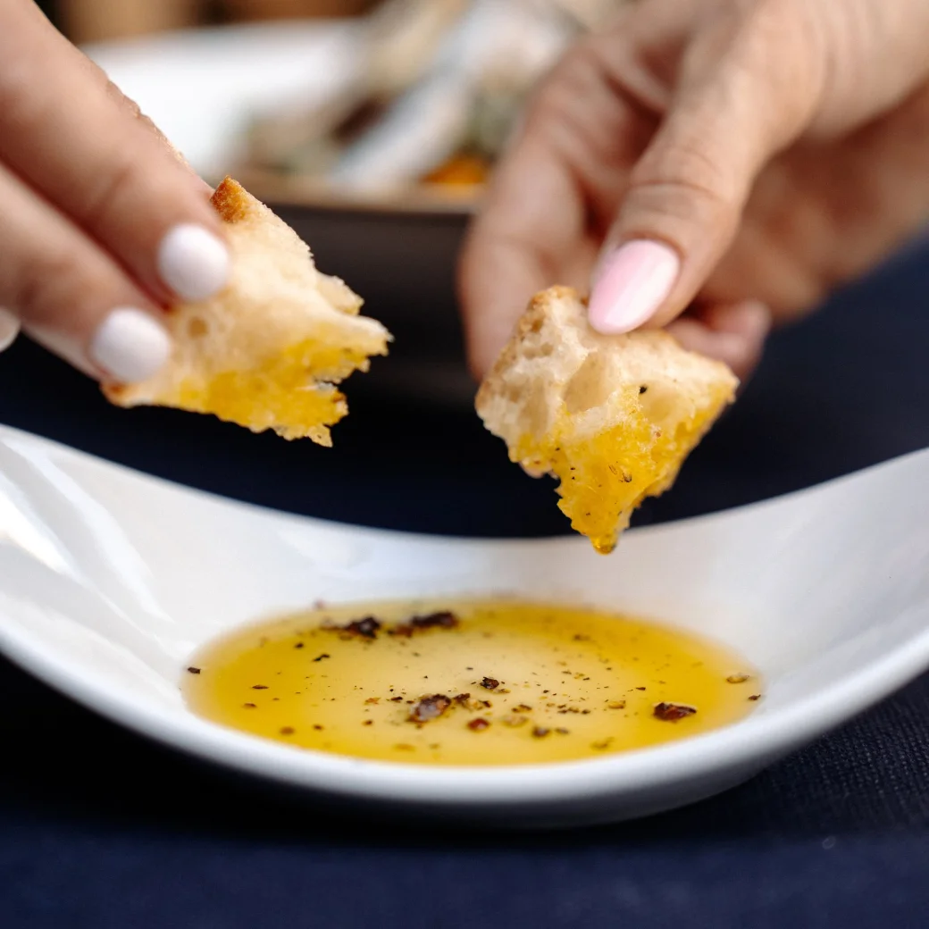 Bread being dipped into a dish of extra virgin olive oil